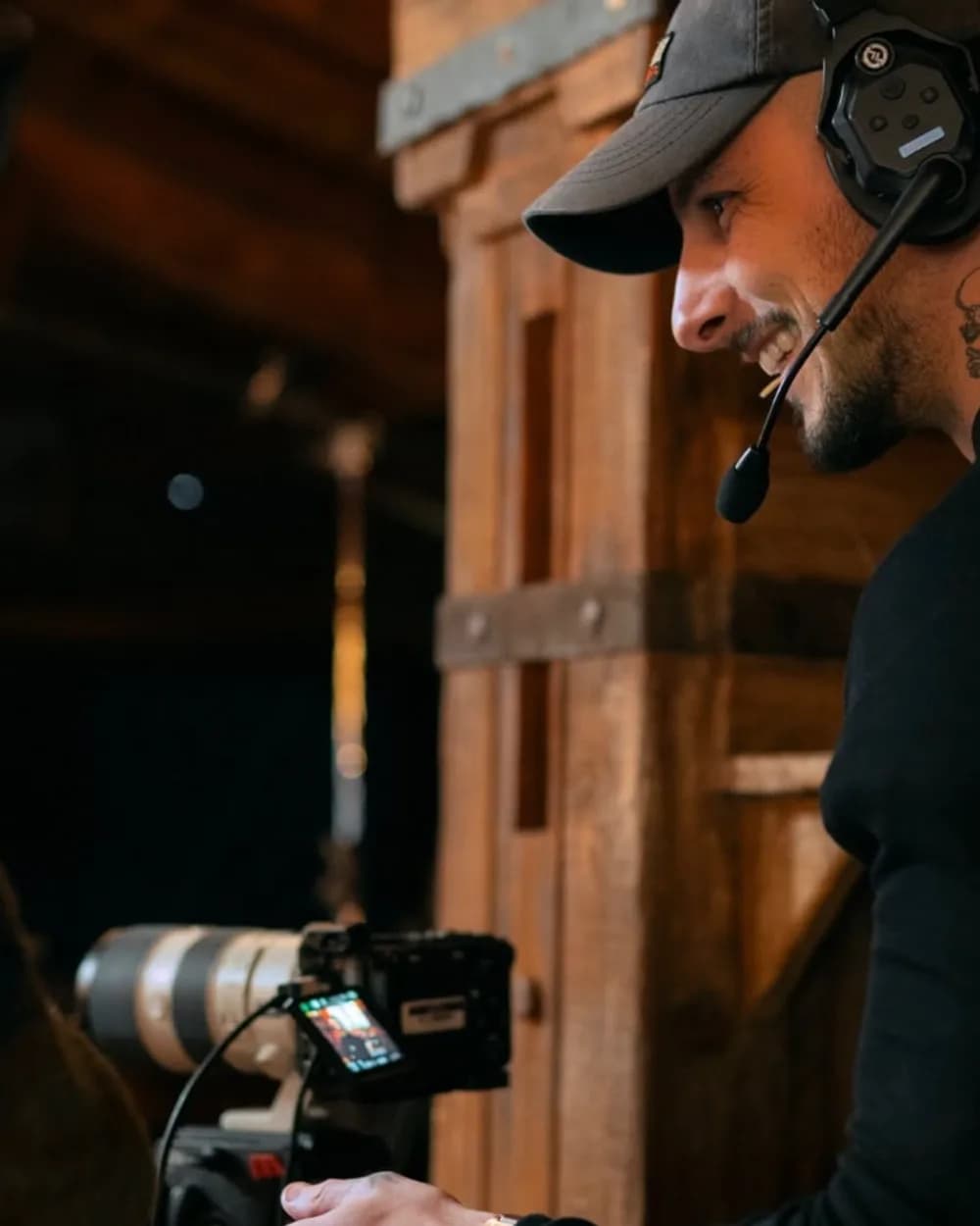 Enzo, souriant, casque sur les oreilles, derrière sa caméra sur un plateau